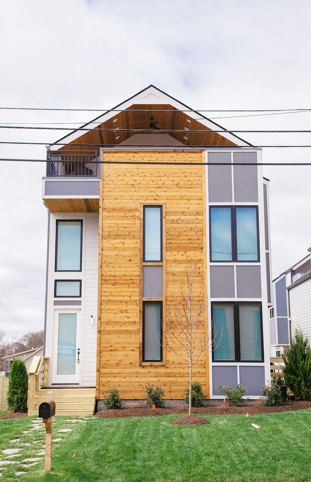 Imagen de fachada de casa contemporánea grande de tres plantas con revestimiento de madera y tejado a dos aguas