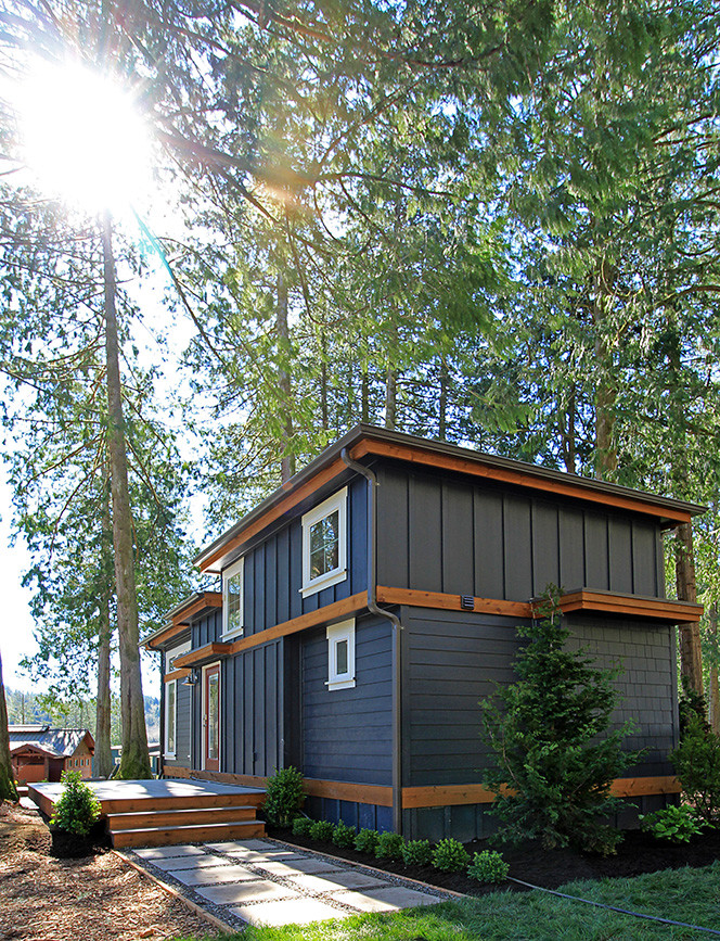 Пример оригинального дизайна: маленький, одноэтажный, синий дом в стиле кантри с облицовкой из ЦСП и плоской крышей для на участке и в саду