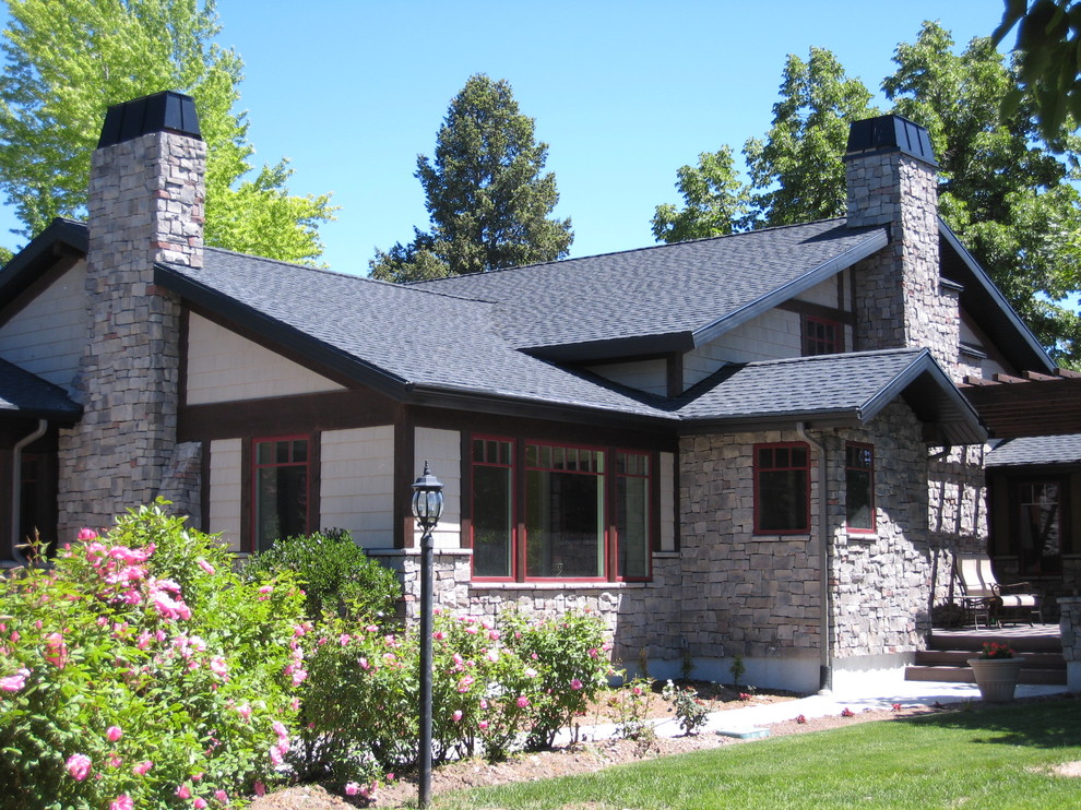 На фото: большой, двухэтажный, серый частный загородный дом в классическом стиле с облицовкой из камня, двускатной крышей и крышей из гибкой черепицы с