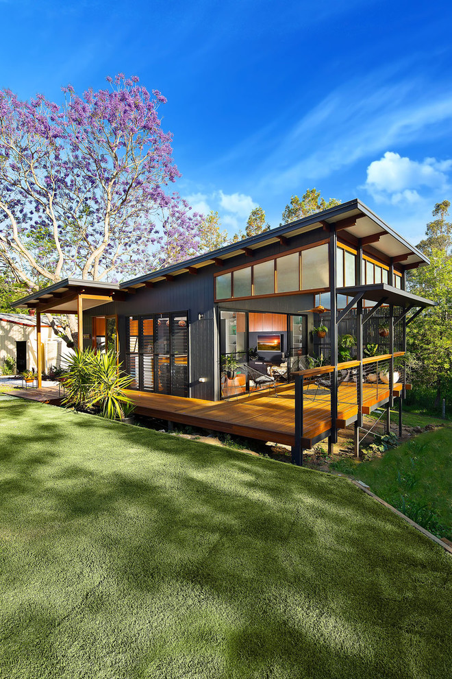 Photo of a small and black modern bungalow detached house in Brisbane with concrete fibreboard cladding, a flat roof and a metal roof.