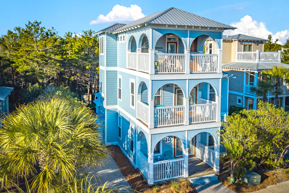 Diseño de fachada de casa azul costera de tamaño medio de tres plantas con revestimientos combinados y tejado de metal