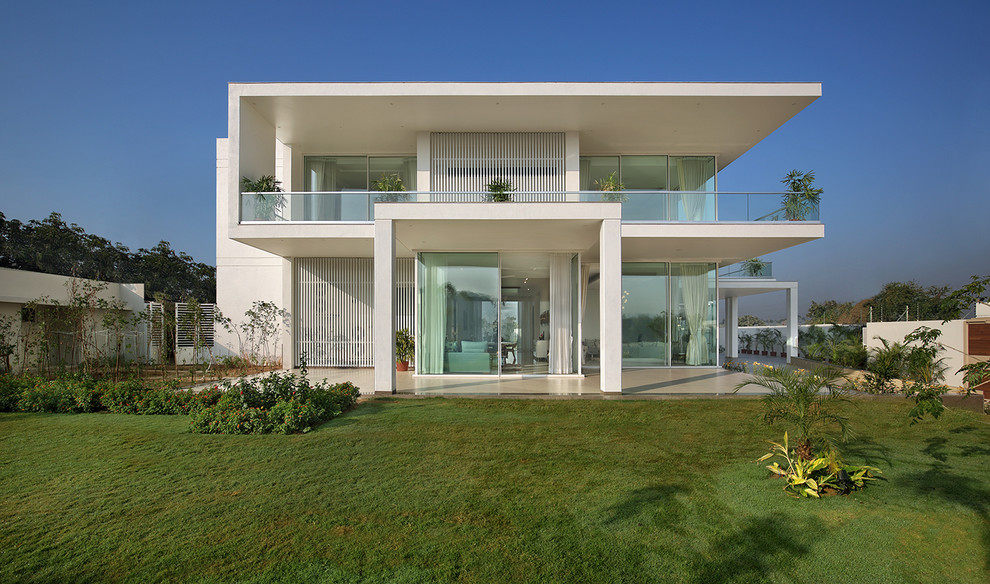Пример оригинального дизайна: белый, двухэтажный частный загородный дом в стиле модернизм с плоской крышей