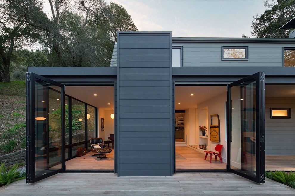 Cette image montre une grande façade de maison grise minimaliste à un étage avec un revêtement en vinyle et un toit de Gambrel.