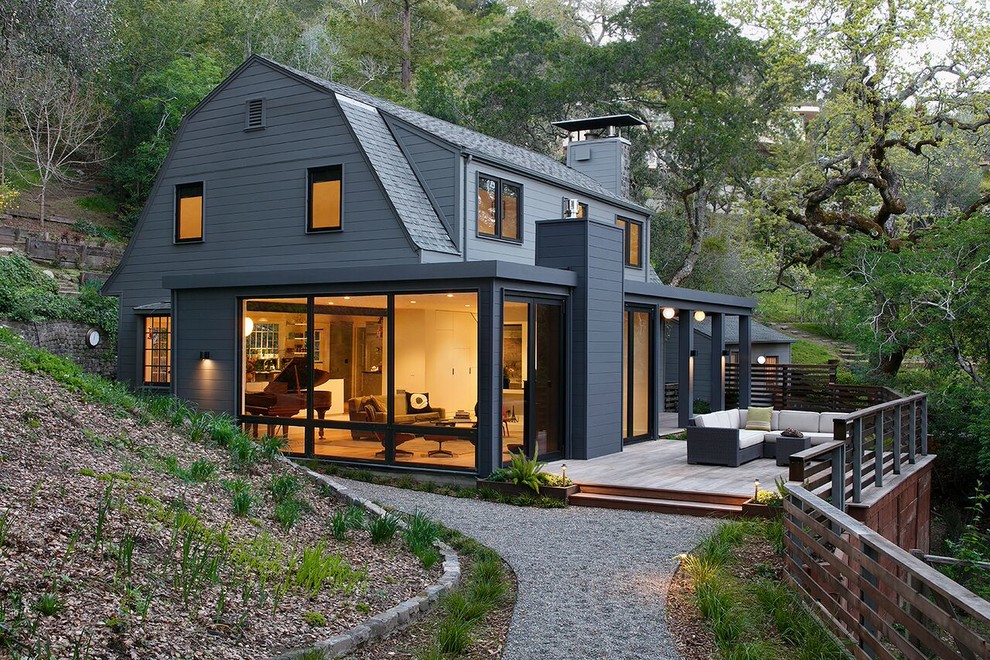 Cette image montre une grande façade de maison grise minimaliste à un étage avec un revêtement en vinyle et un toit de Gambrel.