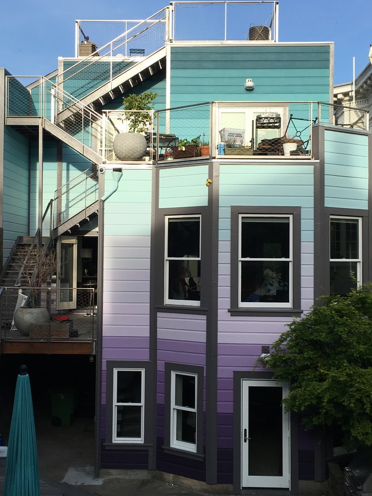This is an example of a large eclectic render terraced house in San Francisco with three floors, a purple house and a flat roof.