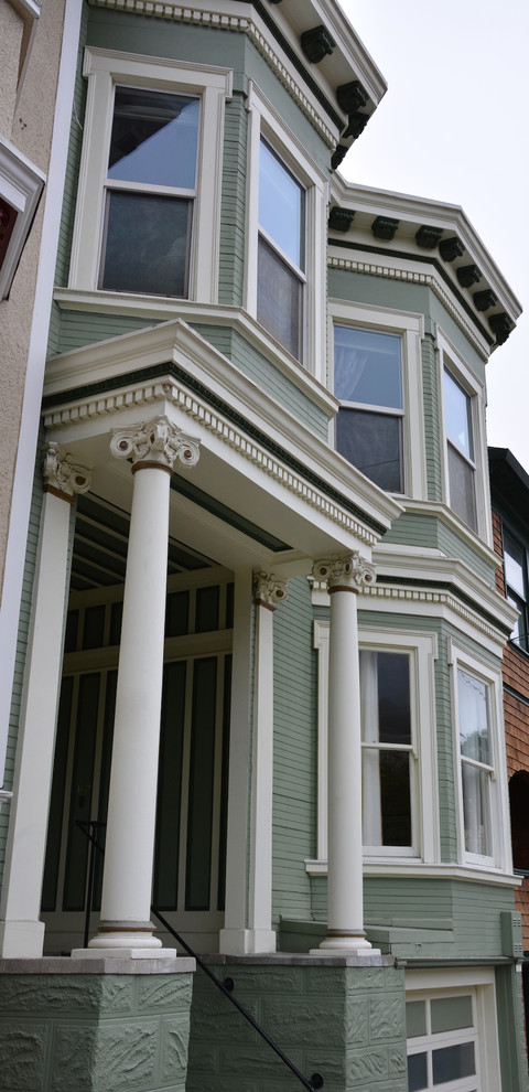 Immagine della facciata di una casa verde vittoriana a due piani di medie dimensioni con rivestimento in legno e tetto piano