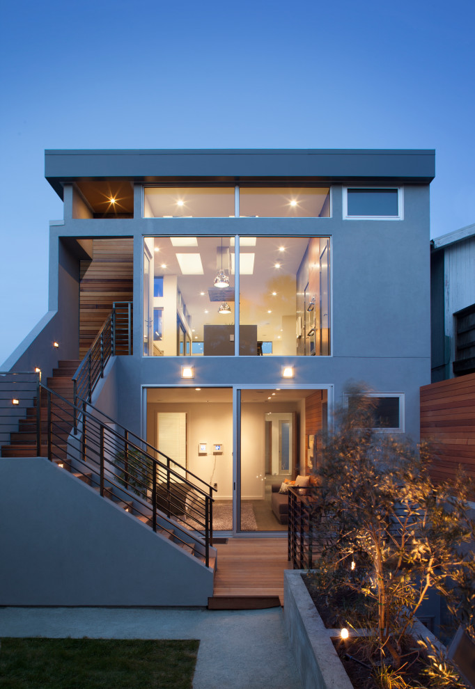 Idée de décoration pour une façade de maison grise design en stuc de taille moyenne et à un étage avec un toit plat.