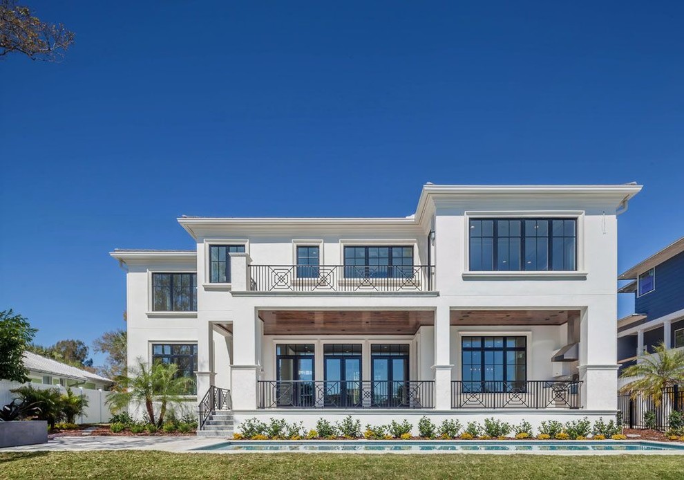Inspiration for a large modern white two-story stucco house exterior remodel in Tampa with a hip roof and a shingle roof