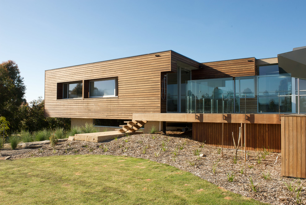 Diseño de fachada marrón contemporánea a niveles con revestimiento de madera y tejado plano