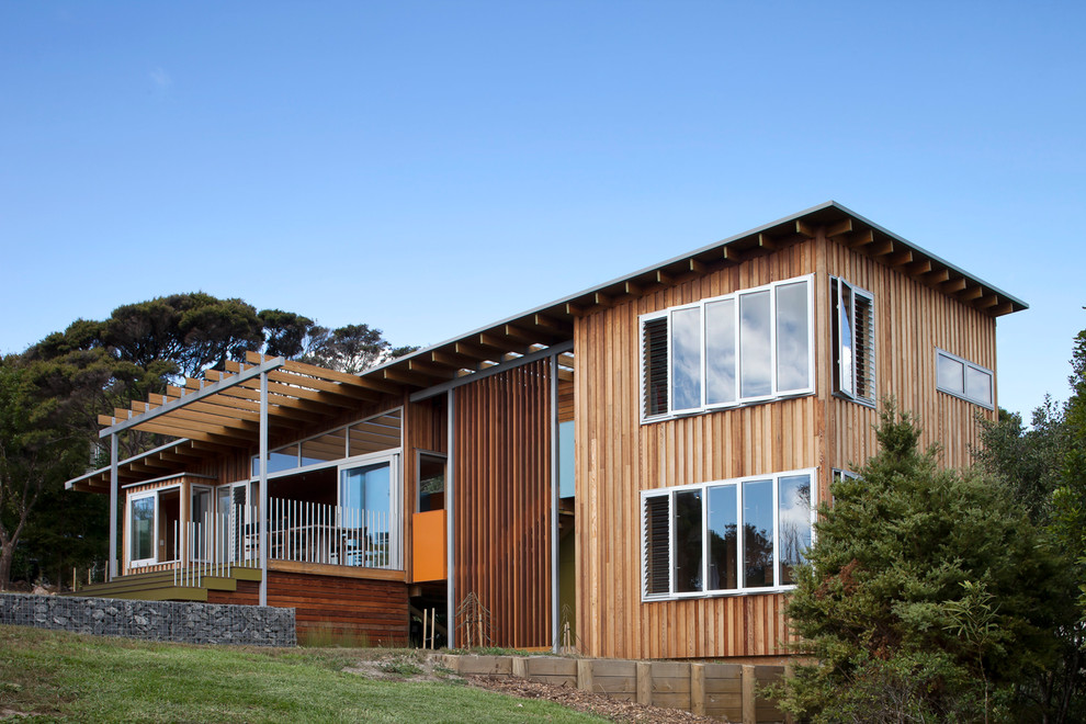 Beach style two floor house exterior in Auckland with wood cladding and a flat roof.