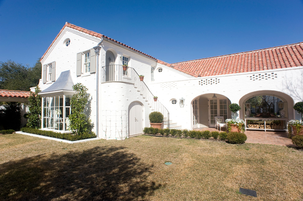 Ejemplo de fachada de casa blanca mediterránea grande de dos plantas con revestimiento de ladrillo, tejado a dos aguas y tejado de teja de barro