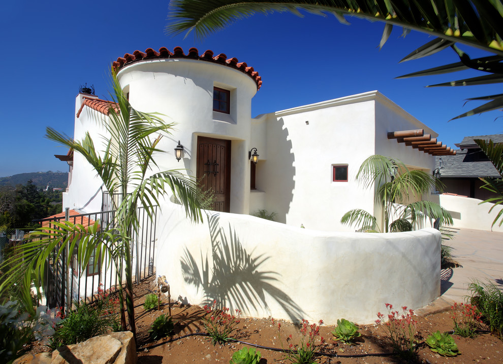 Diseño de fachada de casa blanca mediterránea de tamaño medio de una planta con revestimiento de estuco y tejado de teja de barro