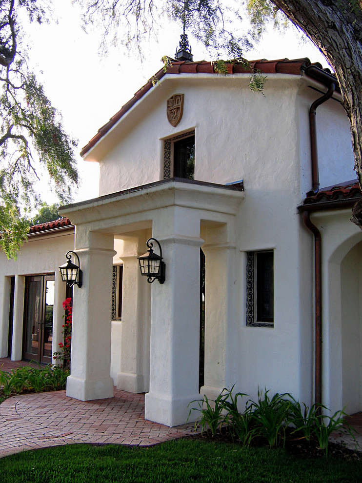 На фото: одноэтажный, белый частный загородный дом среднего размера в средиземноморском стиле с облицовкой из цементной штукатурки, полувальмовой крышей и черепичной крышей с