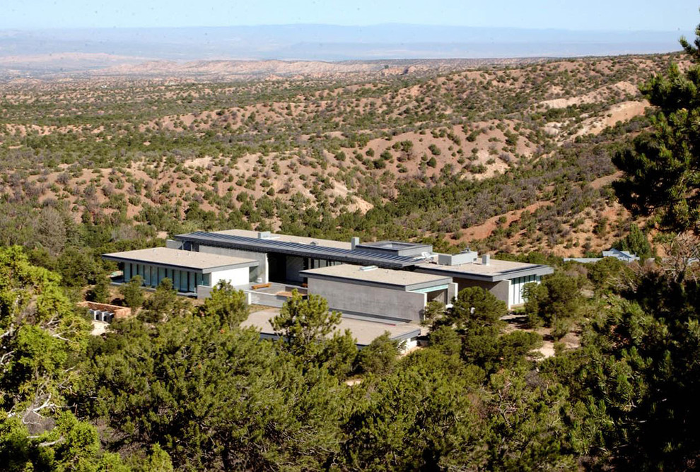 Huge trendy gray split-level glass exterior home photo in Albuquerque with a tile roof