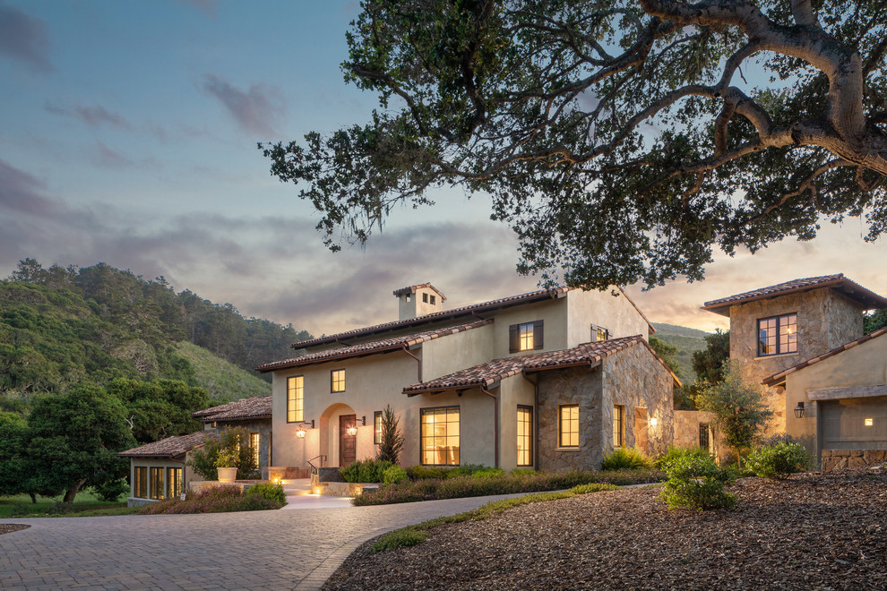 Large mediterranean beige two-story stucco exterior home idea in Orange County with a tile roof