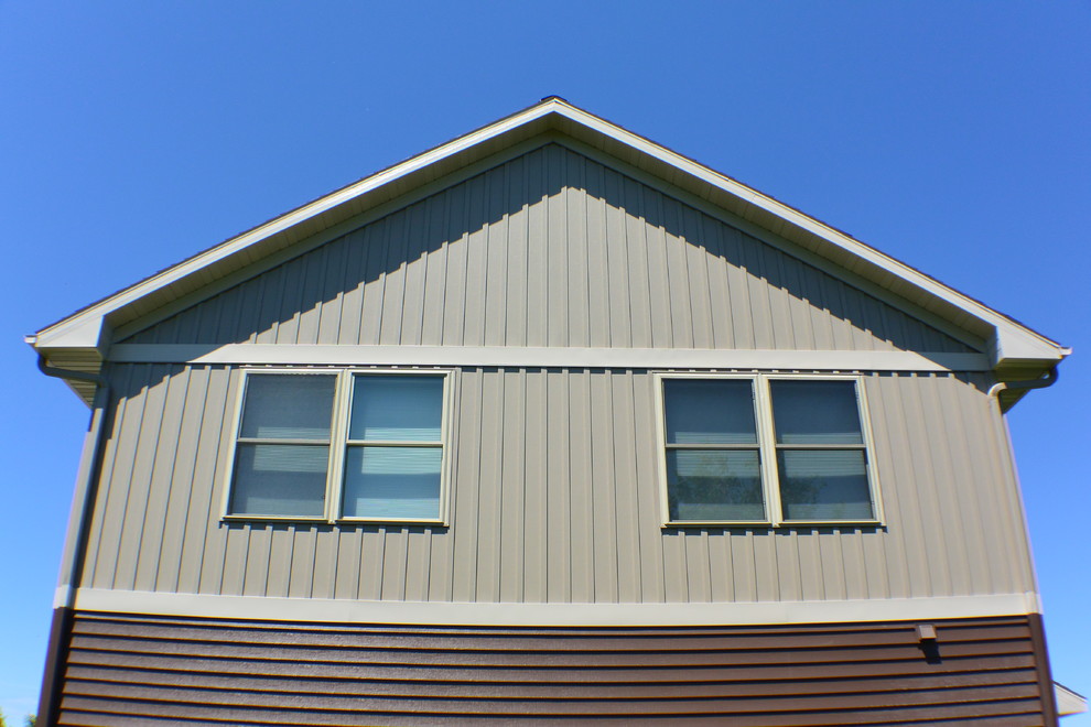 Cette image montre une façade de maison métallique et marron minimaliste de taille moyenne et à un étage avec un toit à deux pans.