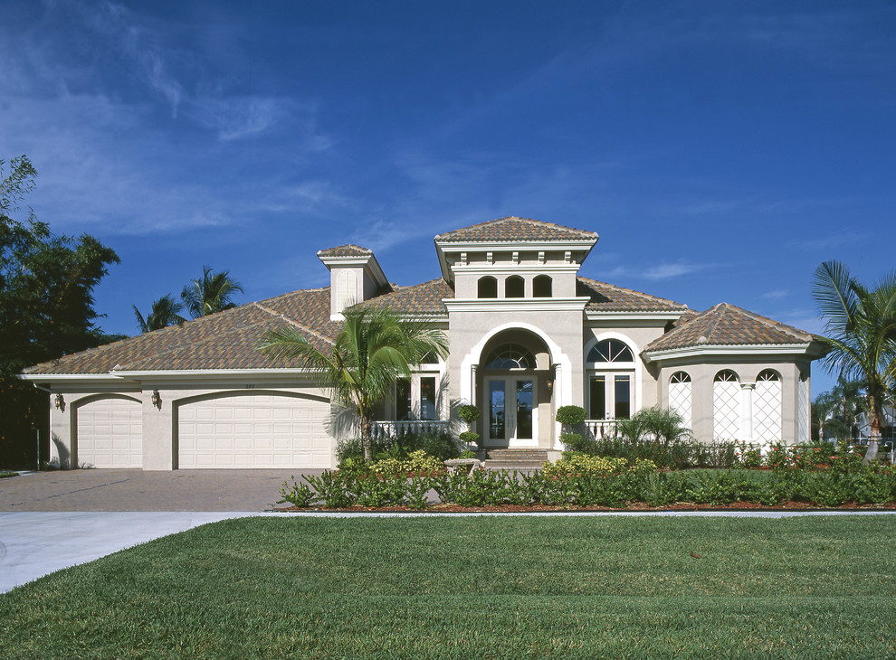 Inspiration for a large mediterranean beige one-story stucco exterior home remodel in Miami with a hip roof