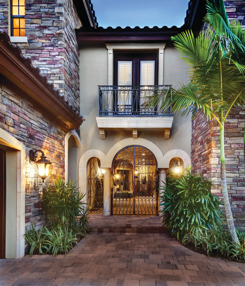 Example of a large tuscan beige two-story mixed siding exterior home design in Miami with a hip roof