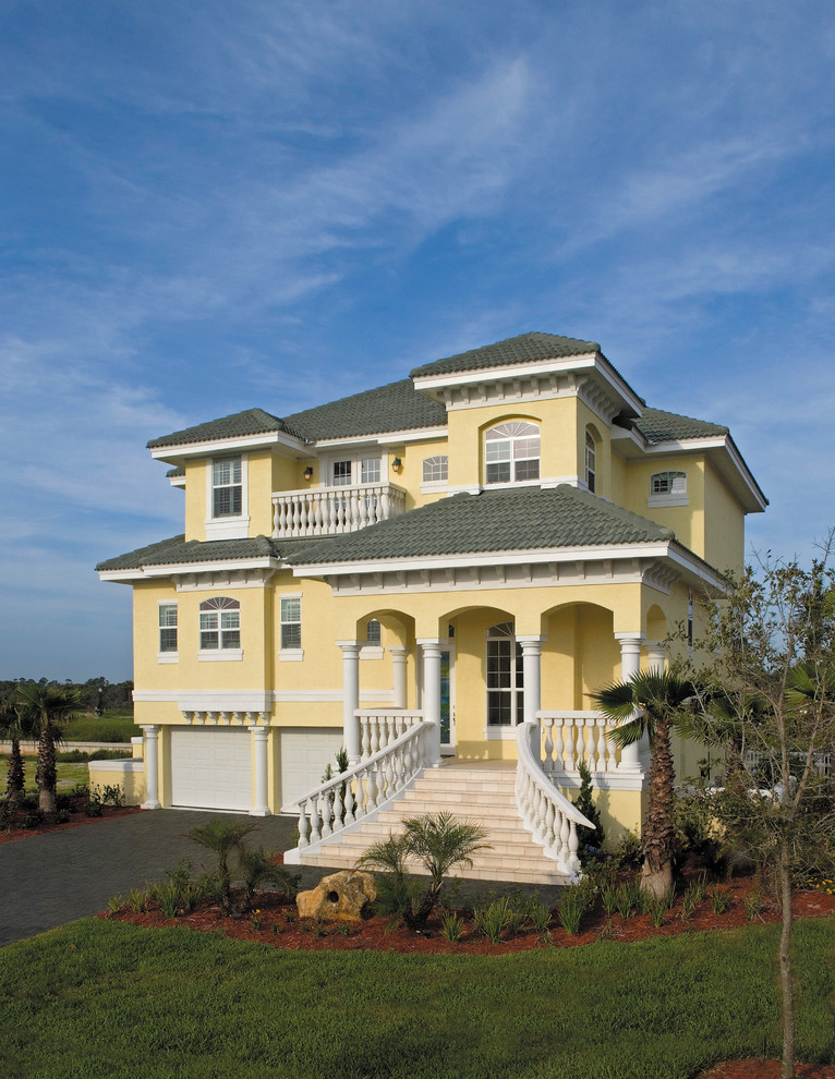 Aménagement d'une grande façade de maison jaune bord de mer en stuc à deux étages et plus.