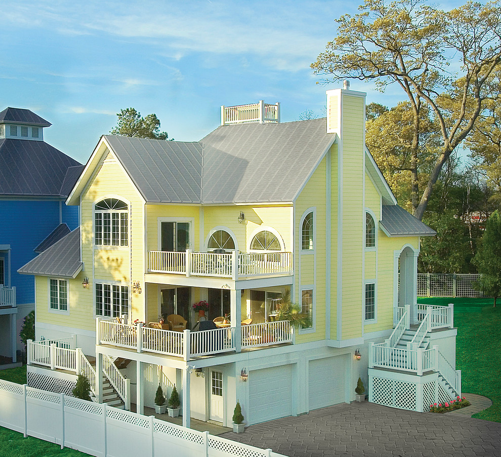 Idee per la facciata di una casa grande gialla stile marinaro a tre piani con rivestimento in vinile