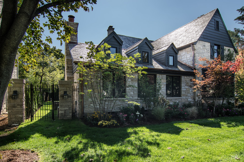Diseño de fachada de casa beige clásica renovada grande de una planta con revestimiento de piedra, tejado a dos aguas y techo verde