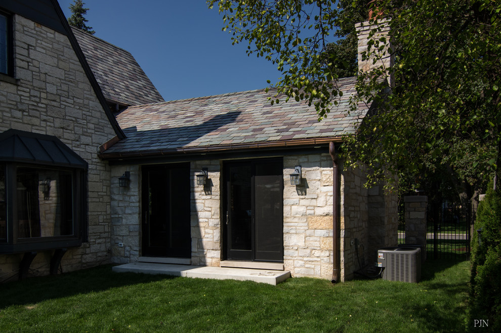Idée de décoration pour une grande façade de maison beige tradition en pierre de plain-pied avec un toit à deux pans et un toit végétal.