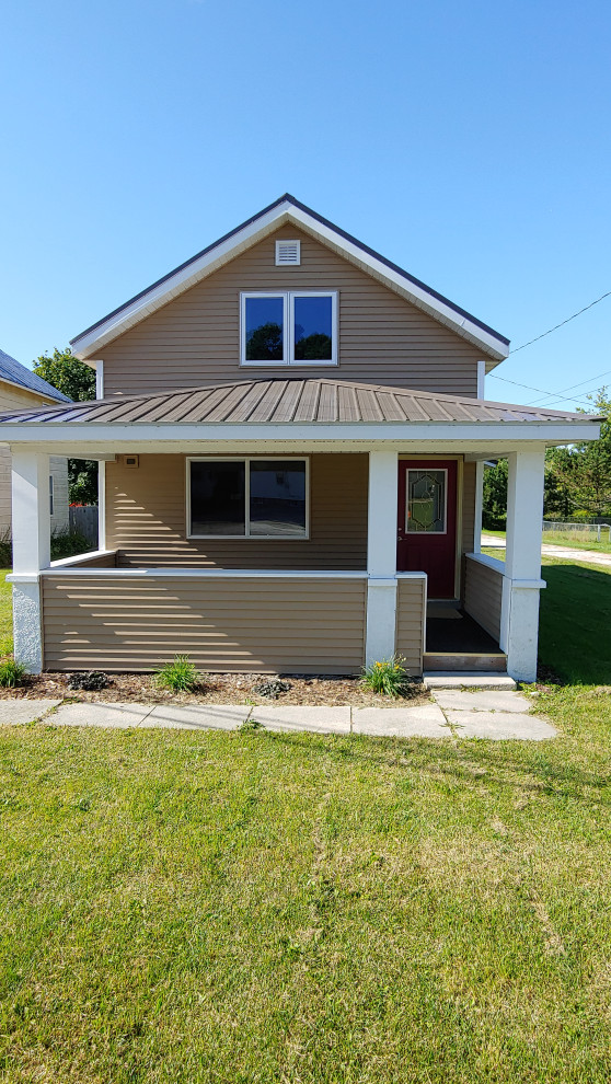 Foto de fachada de casa marrón de estilo de casa de campo pequeña de dos plantas con revestimiento de vinilo, tejado a dos aguas y tejado de metal