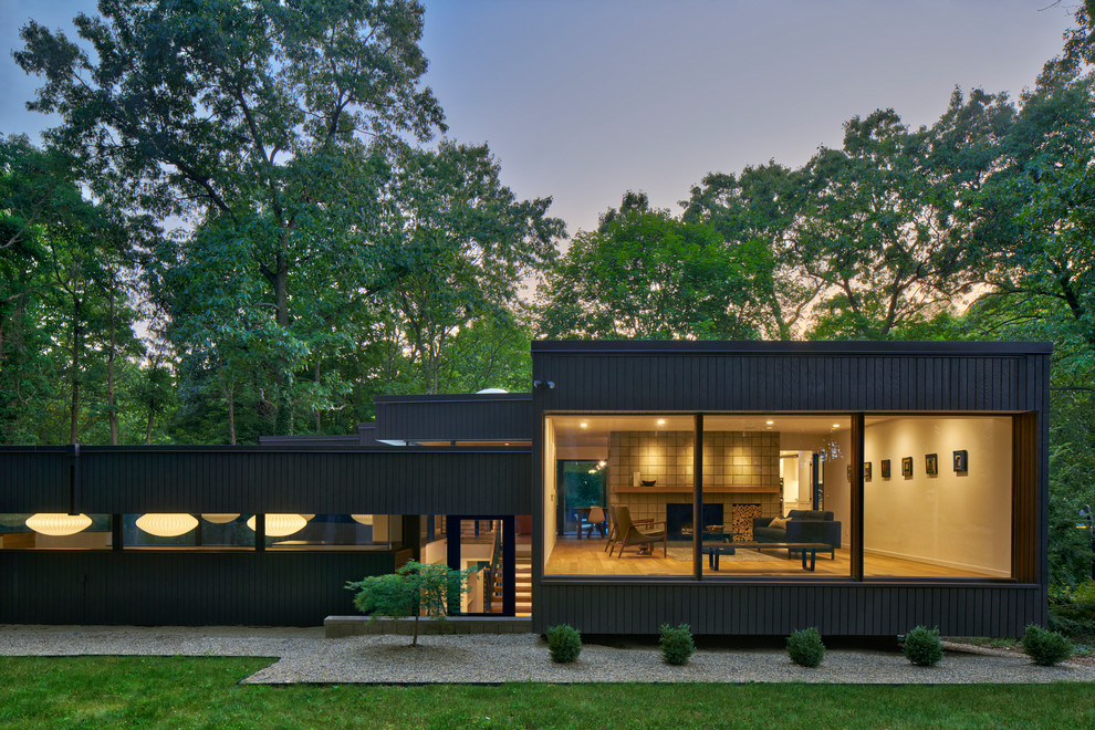 Стильный дизайн: двухэтажный, черный частный загородный дом в стиле ретро с плоской крышей - последний тренд