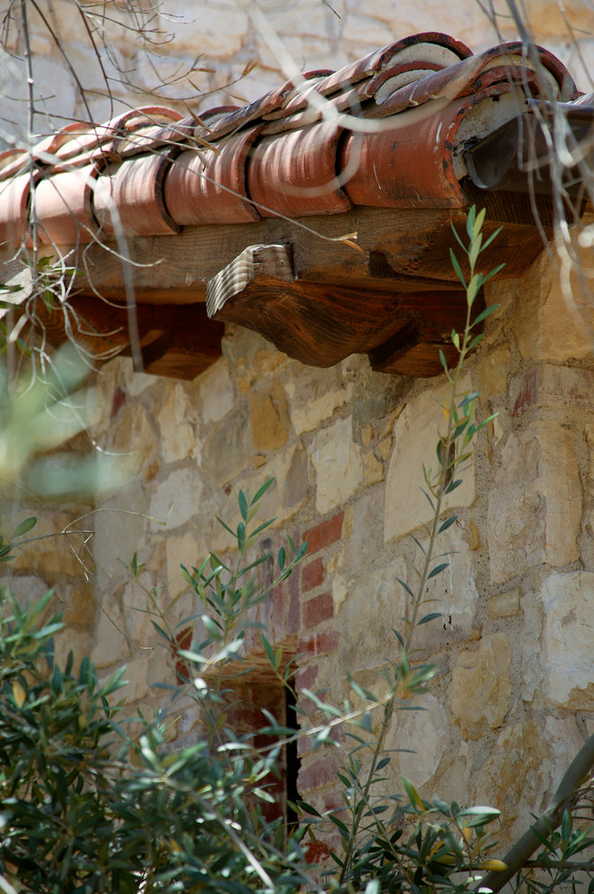 Idee per la facciata di una casa mediterranea a tre piani con rivestimento in pietra e tetto a capanna