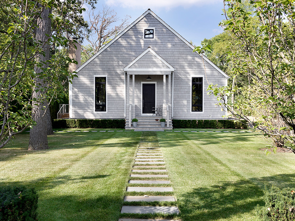 На фото: двухэтажный, серый частный загородный дом в скандинавском стиле с двускатной крышей