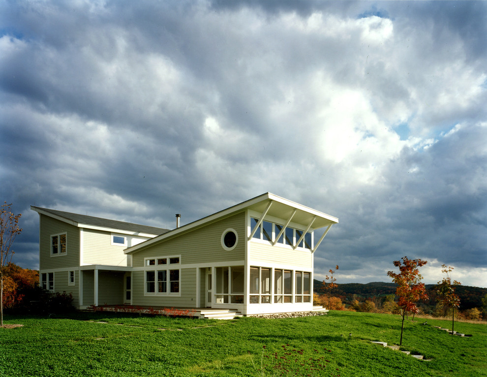Cette image montre une façade de maison grise minimaliste en bois à un étage.