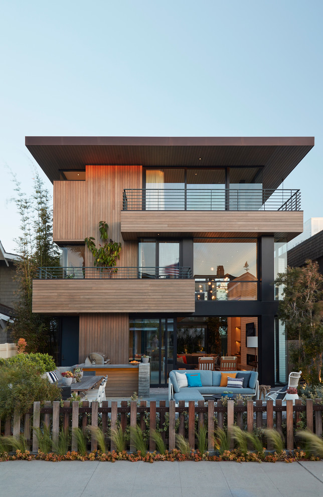 Diseño de fachada de casa marrón contemporánea de tres plantas con revestimiento de madera y tejado plano