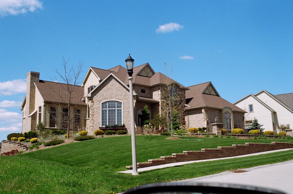 Elegant brown split-level brick exterior home photo in Other