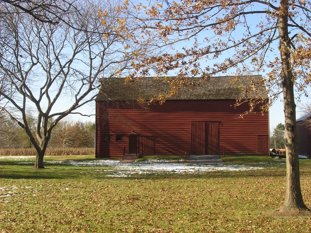Immagine della facciata di una casa grande rossa country a un piano con rivestimento in legno e tetto a capanna