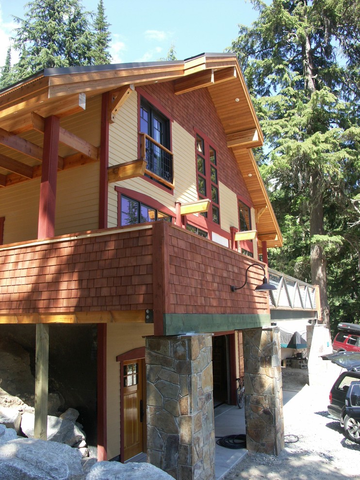 Idée de décoration pour une façade de maison chalet en bois de taille moyenne et à un étage.