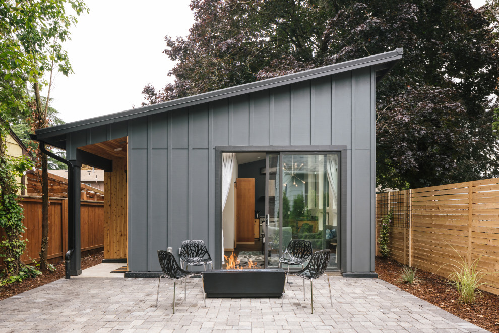 Exempel på ett litet modernt grått hus, med allt i ett plan, pulpettak och tak i metall