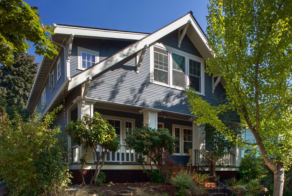 На фото: двухэтажный, деревянный, синий дом в классическом стиле с двускатной крышей с