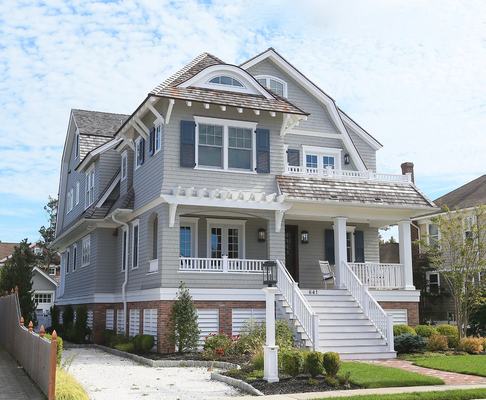 Example of a beach style beige house exterior design in New York with a gambrel roof and a shingle roof