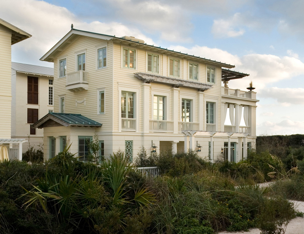 Cette image montre une façade de maison beige marine à deux étages et plus avec un toit à deux pans.