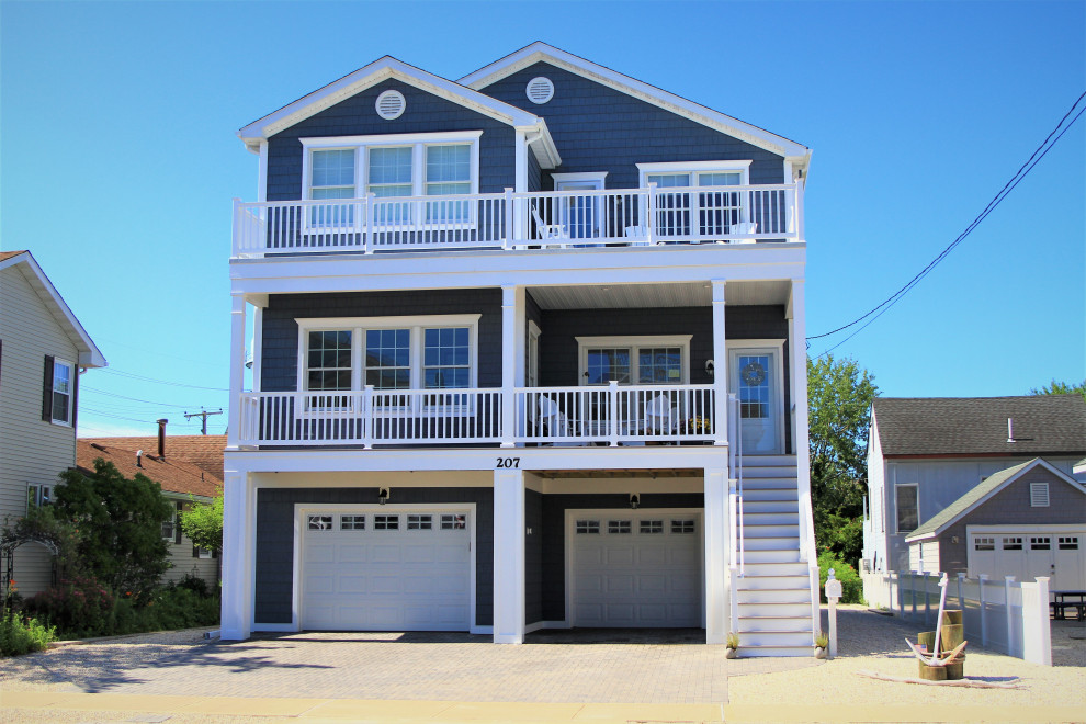 Imagen de fachada de casa azul costera grande de tres plantas con revestimiento de vinilo y tejado de teja de madera