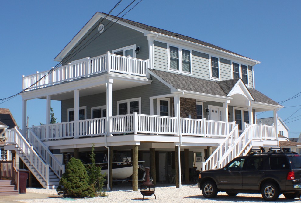 Cette image montre une façade de maison verte marine de taille moyenne et à un étage avec un revêtement en vinyle et un toit à deux pans.
