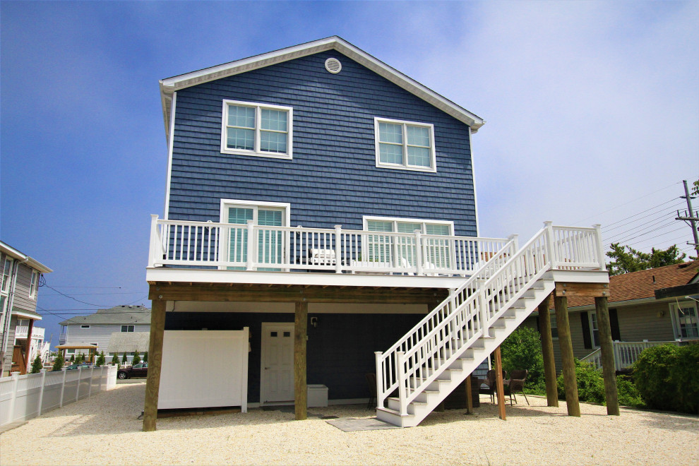 Imagen de fachada de casa azul marinera grande de tres plantas con revestimiento de vinilo, tejado a dos aguas y tejado de teja de madera
