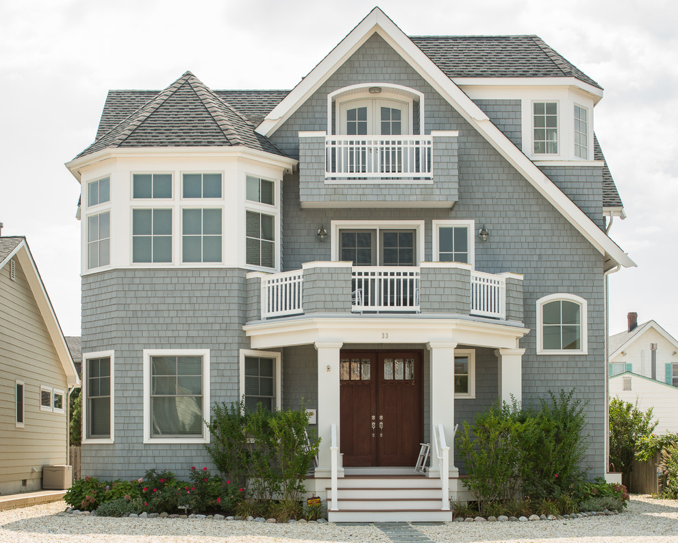 Cette image montre une façade de maison grise marine en bois à deux étages et plus.