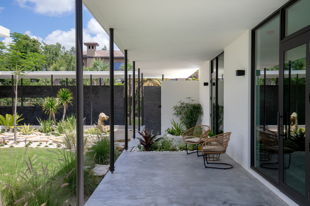 Idee per un grande patio o portico minimalista in cortile con lastre di cemento e un parasole