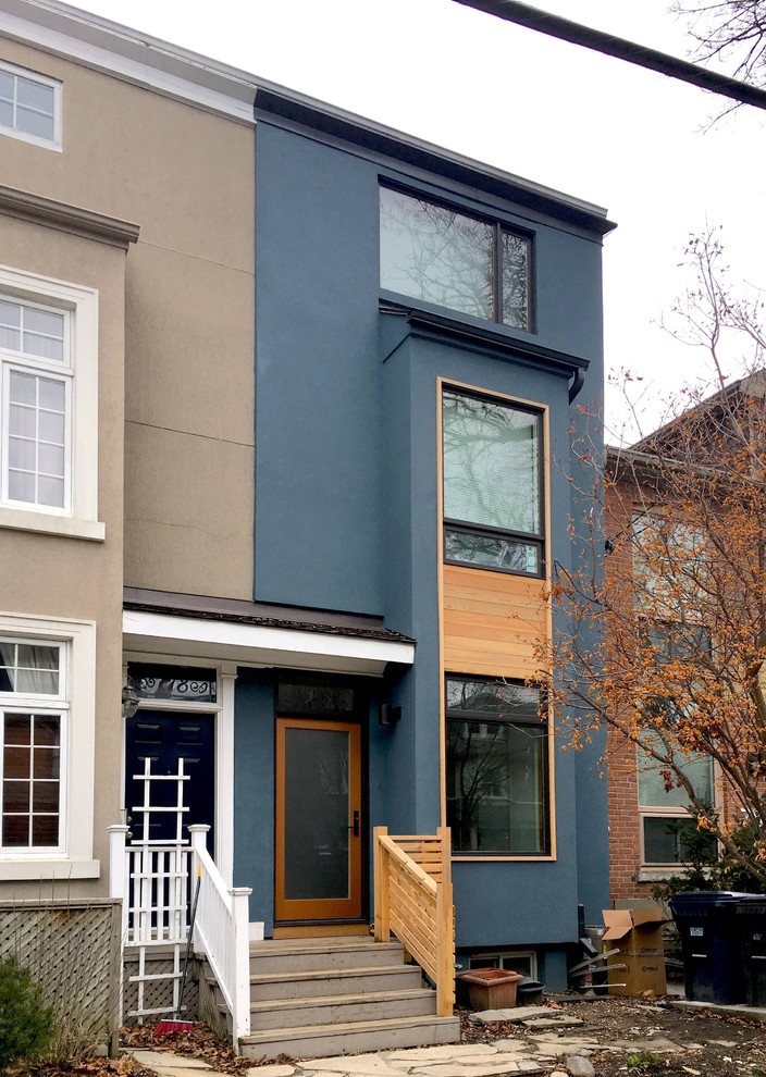 Cette image montre une façade de maison de ville bleue minimaliste en stuc de taille moyenne et à un étage avec un toit plat et un toit en métal.
