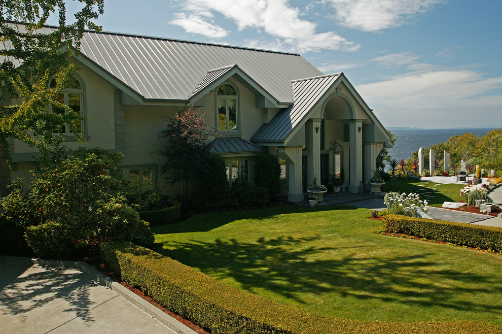 Huge traditional gray two-story stucco house exterior idea in Seattle with a clipped gable roof and a metal roof