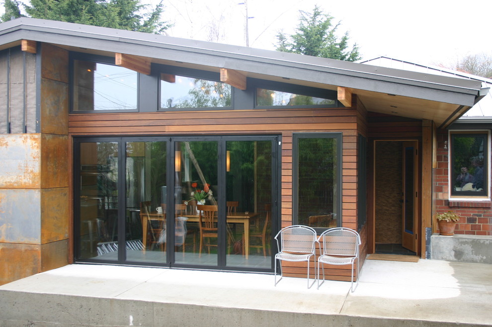 Идея дизайна: одноэтажный, коричневый дом среднего размера в современном стиле с облицовкой из ЦСП и двускатной крышей