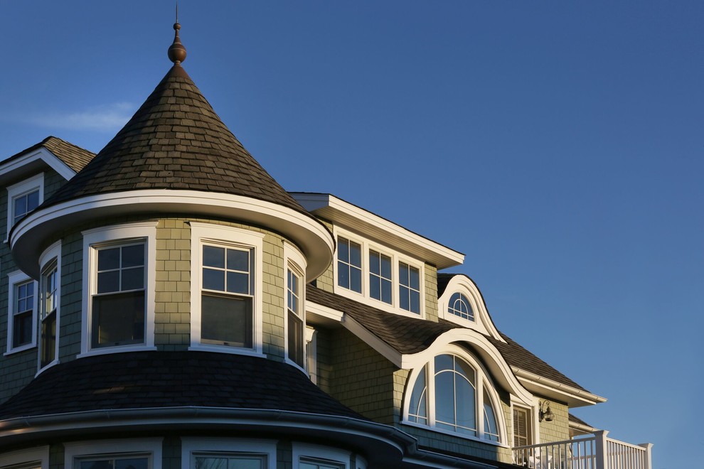 Imagen de fachada de casa gris campestre grande de tres plantas con revestimiento de madera y tejado de teja de madera