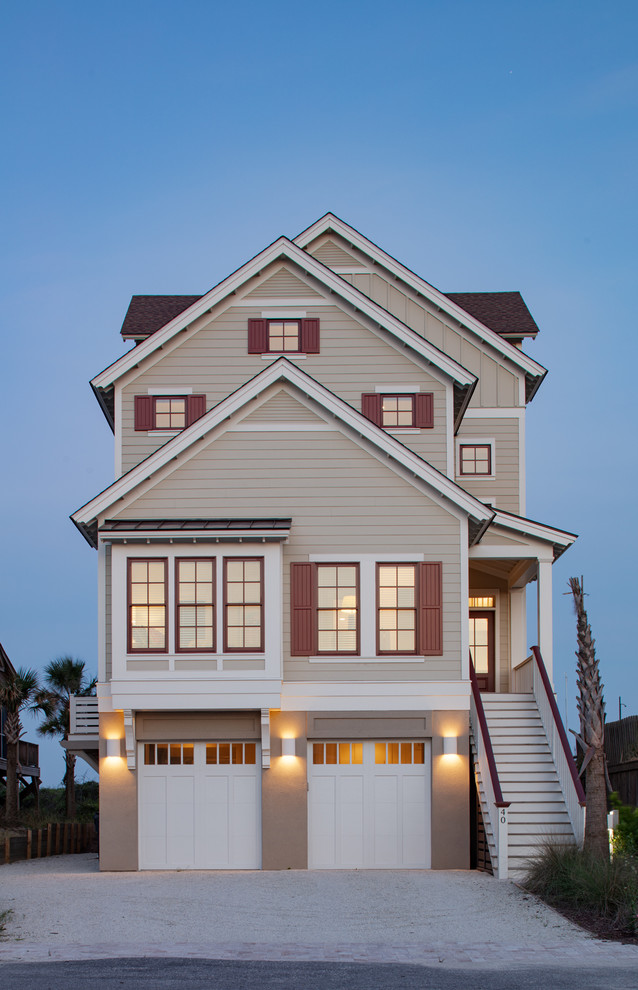 Imagen de fachada de casa beige costera de tamaño medio de tres plantas con revestimiento de aglomerado de cemento, tejado a dos aguas y tejado de teja de madera
