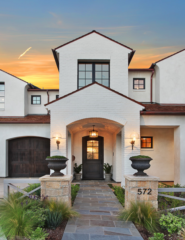 Inspiration for a white nautical two floor brick house exterior in Orange County with a pitched roof.